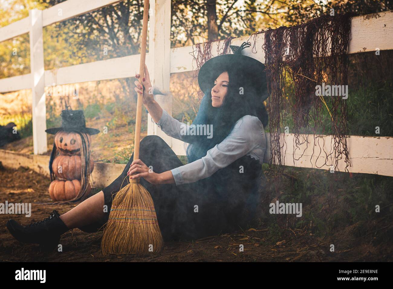 Die Hexe Sitzt Am Zaun Auf Dem Hof Und Bläst Den Rauch Mit Einem Besen Stockfotografie Alamy 