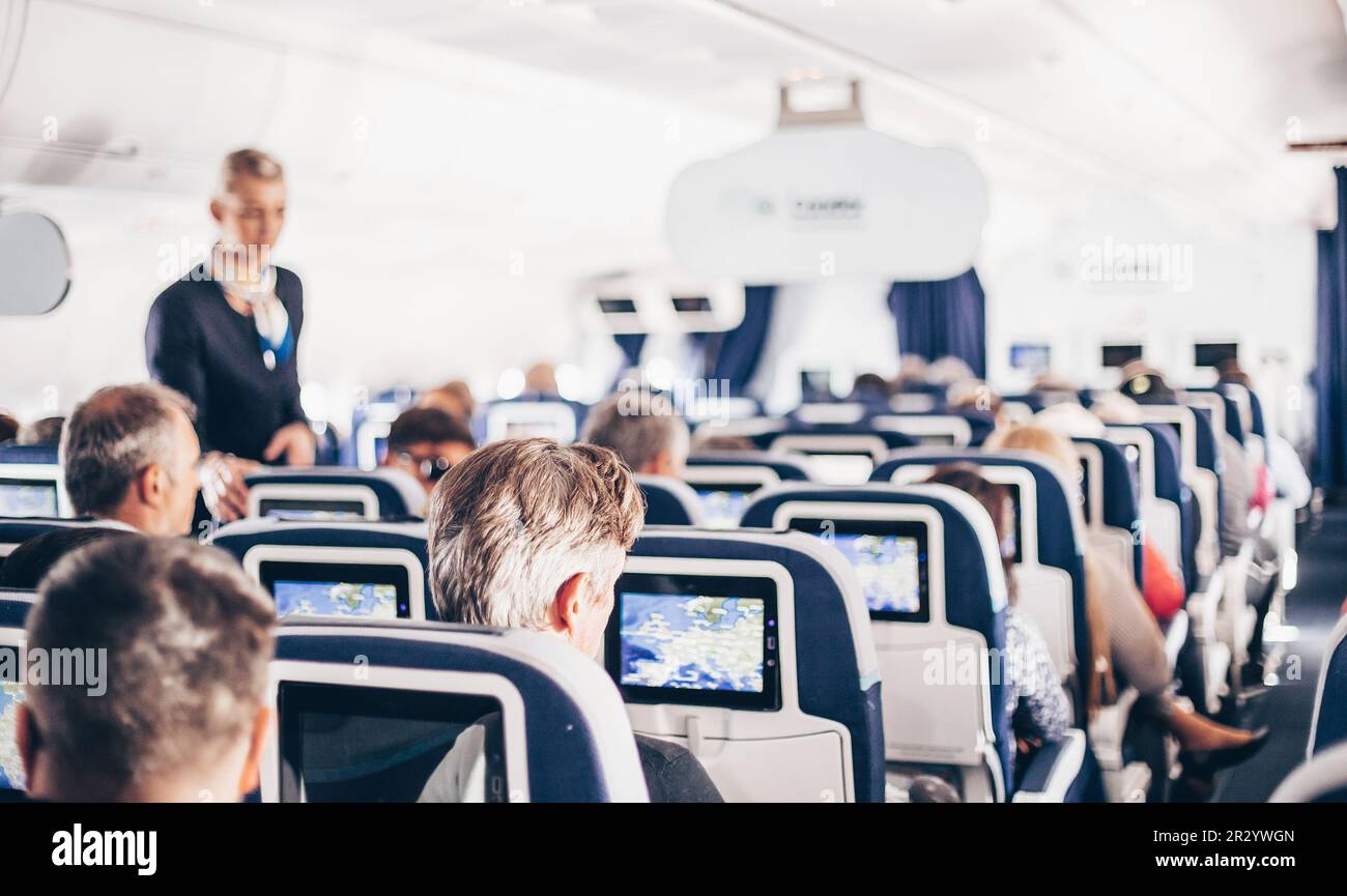 Flugzeuginnenraum Mit Passagieren Auf Sitzen Und Stewardess In Uniform