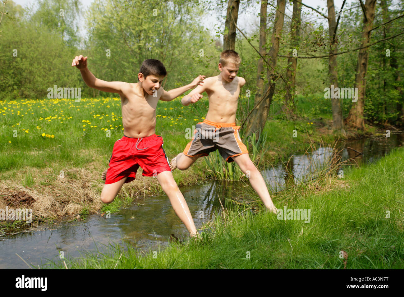 Zwei Jungen Barfuß über Einen Bach Springen Stockfotografie Alamy