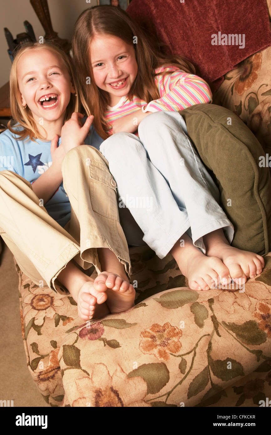 Zwei Junge Mädchen Barfuß Kichern Auf Couch Stockfotografie Alamy 
